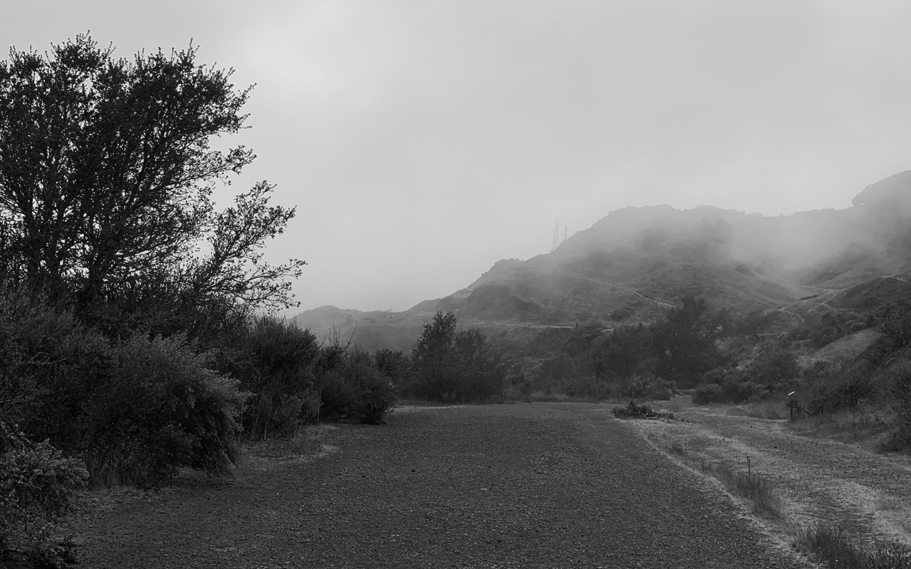 Time of Ghosts gravel path with mountain and fog in distance
